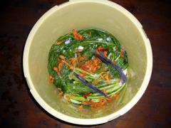 一晩、塩して重しを載せ、水分を抜いた野沢菜に、昆布、トウガラシとともに柿皮を振りかけて漬け込みます